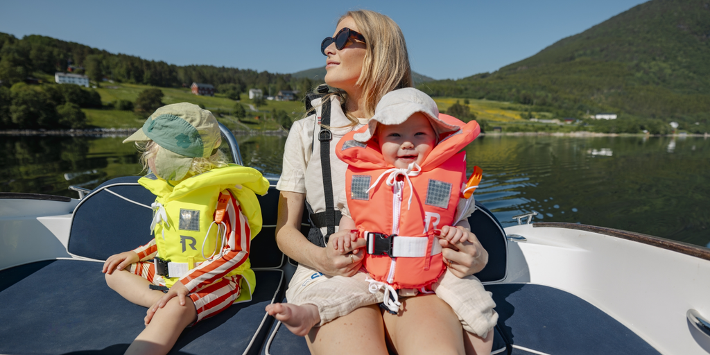 En baby og et ungt barn har på seg redningsvest fra Regatta på båttur